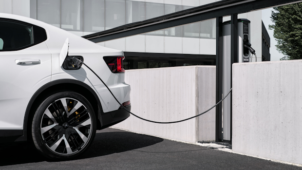 Polestar car charging at a station outdoors near a modern building.